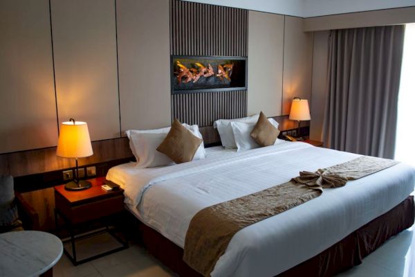 A cozy hotel room featuring a large bed with brown accents, bedside tables, lamps, and a decorative wall feature.