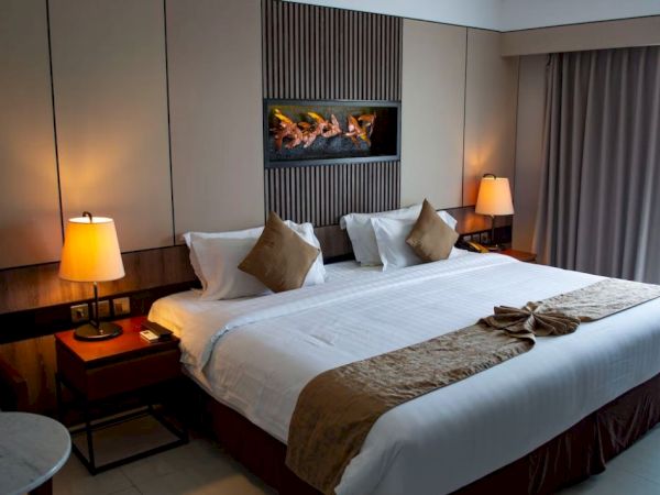 A cozy hotel room featuring a large bed with brown accents, bedside tables, lamps, and a decorative wall feature.