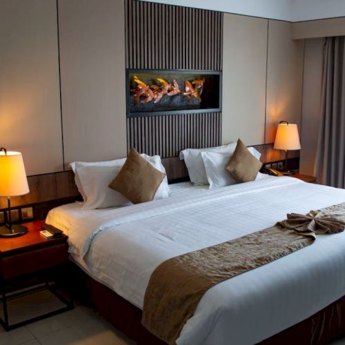 A cozy hotel room featuring a large bed with pillows, bedside tables with lamps, and decorative elements on the walls and bed.