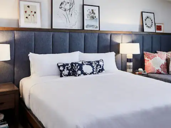 A neatly arranged bedroom features a large bed, bedside tables with lamps, and art on the wall, creating a cozy and inviting atmosphere.