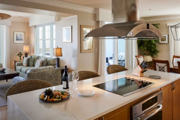 A modern open-concept living space with a kitchen island, dining area, and cozy seating while offering a view of the ocean outside the window.