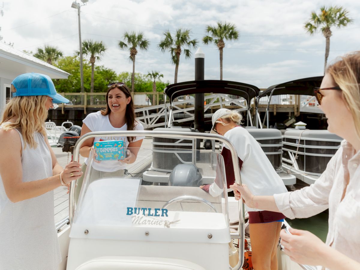 Four people are enjoying a day on a boat at a marina, with palm trees visible.