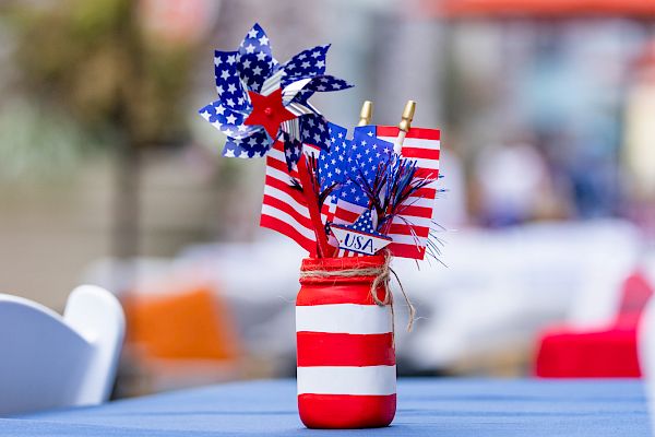 A festive jar with red, white, and blue pinwheels and flags on a table.