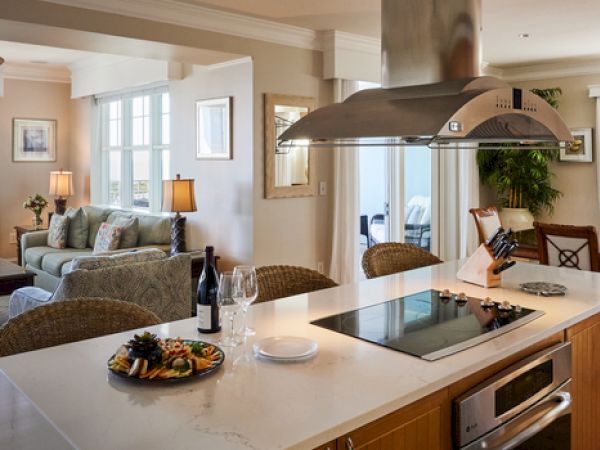 A modern open-concept living space with a kitchen island, dining area, and cozy seating while offering a view of the ocean outside the window.