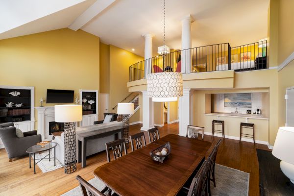 A spacious living room with vaulted ceilings, dining area, loft, modern decor, and warm lighting, creating an inviting atmosphere.