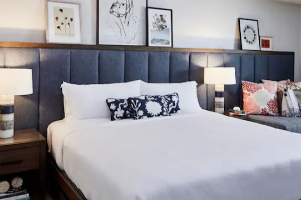 A neatly arranged bedroom features a large bed, bedside tables with lamps, and art on the wall, creating a cozy and inviting atmosphere.