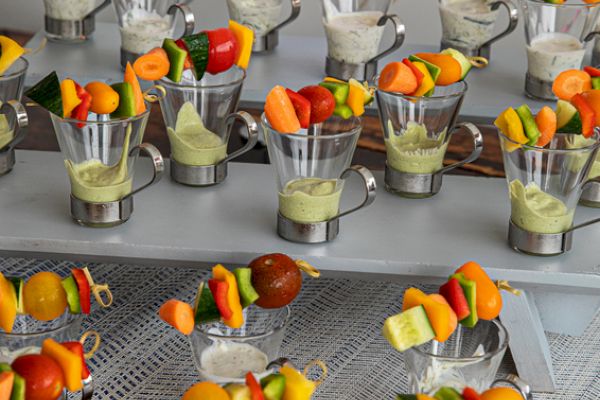 The image shows cups containing vegetable skewers with dip, arranged on a table for serving.