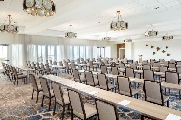 This image shows a conference room setup with chairs, tables, decorative lights, and wall art, ready for a meeting or presentation.