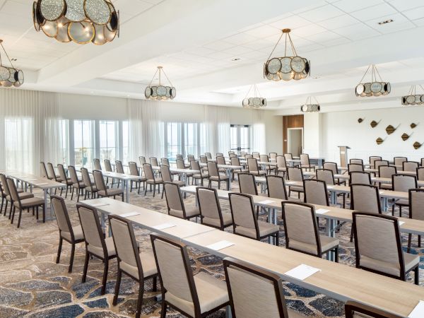 This image shows a conference room setup with chairs, tables, decorative lights, and wall art, ready for a meeting or presentation.