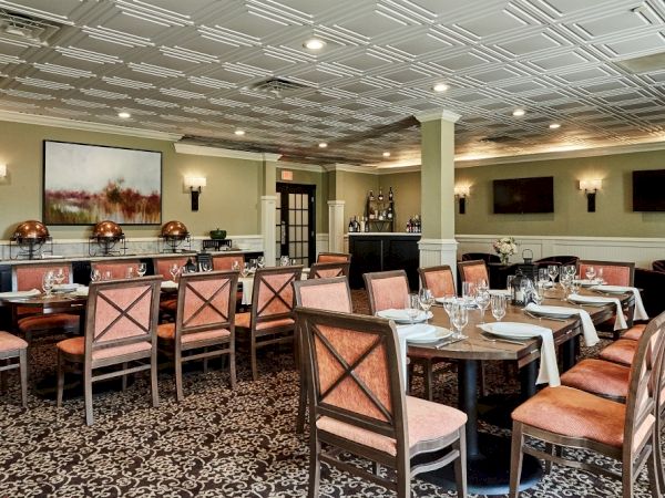 The image shows an elegantly decorated restaurant dining area with arranged tables, chairs, and artwork on walls, perfect for a formal setting.