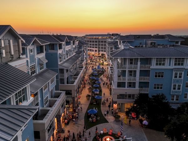 Aerial view of a bustling street lined with buildings, vibrant with activity, under a striking sunset.