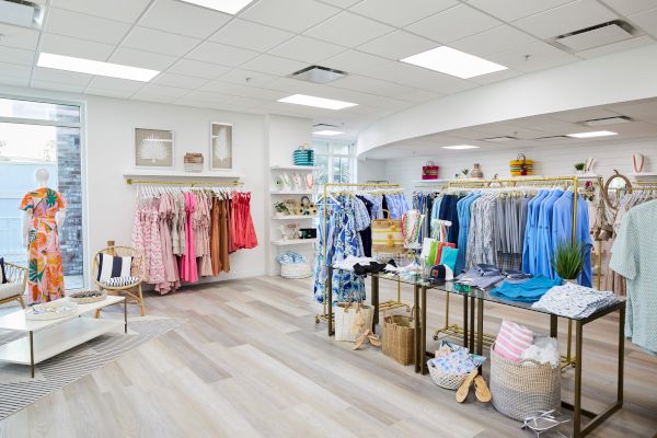 A boutique displaying colorful clothing on racks, with accessories and decor on tables and shelves, creating a bright, inviting atmosphere.
