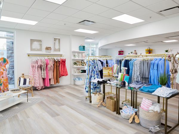 A boutique displaying colorful clothing on racks, with accessories and decor on tables and shelves, creating a bright, inviting atmosphere.