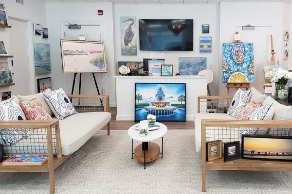A cozy art gallery with sofas, a table, and displayed paintings on the walls and easels enhances the room's ambiance.