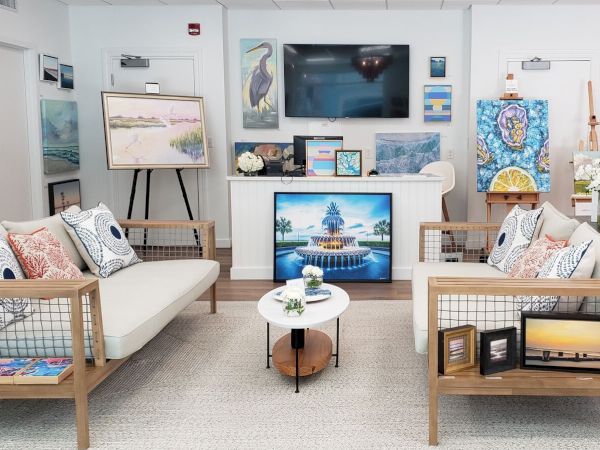 A cozy art gallery with sofas, a table, and displayed paintings on the walls and easels enhances the room's ambiance.