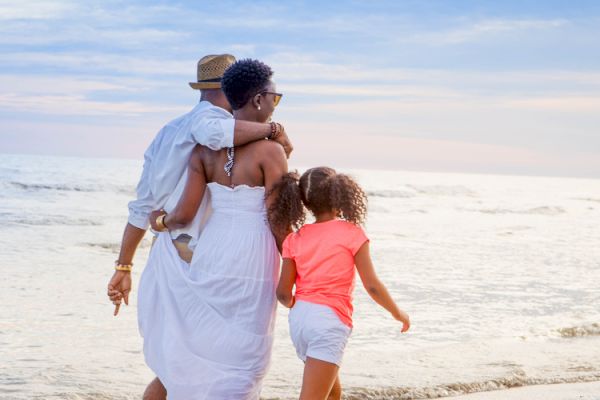 A family walking together on a beach during sunset, enjoying the serene ocean view and sandy shore.
