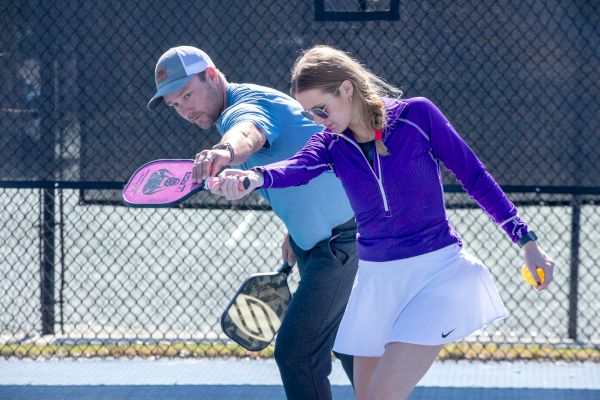 Two people playing pickleball together on a court, holding paddles and focused on the ball.