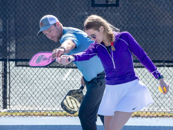 Two people playing pickleball together on a court, holding paddles and focused on the ball.