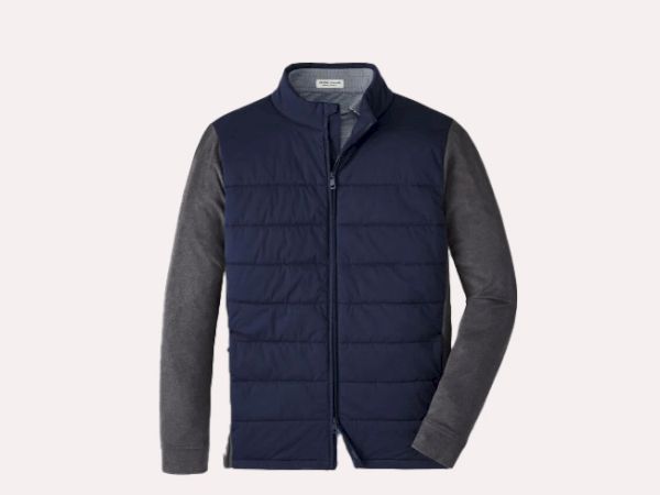 The image shows a navy quilted vest with a gray long-sleeve shirt underneath, designed for layering in cooler weather.