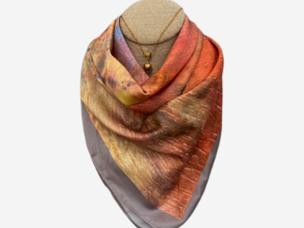 A mannequin with a multicolored scarf draped around its neck and a necklace underneath, displayed against a plain background.