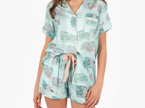 A person is wearing a light blue, short-sleeve, button-up shirt and shorts, featuring a pastel pattern with a pink drawstring.