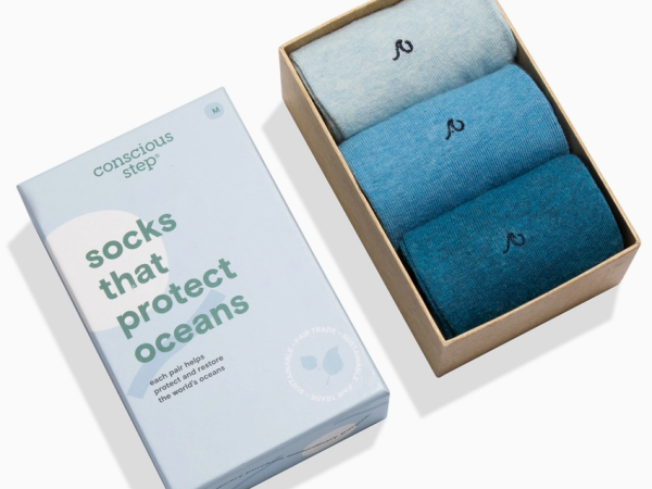 A box set of three blue socks alongside packaging labeled "socks that protect oceans" by Conscious Step.