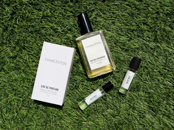 Perfume bottle and packaging on grass with two small sample vials nearby, labeled "CHAMELEON" and "ZOOLOGIST."