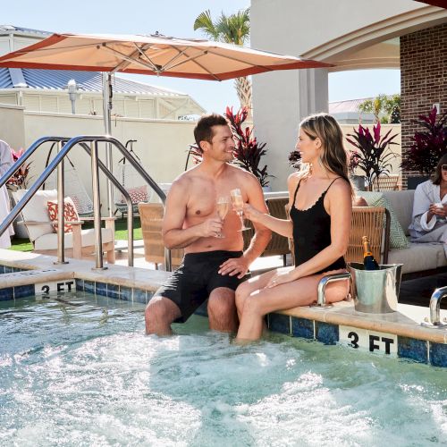 People are enjoying a spa day, sitting by a pool, sipping champagne, and relaxing in robes.
