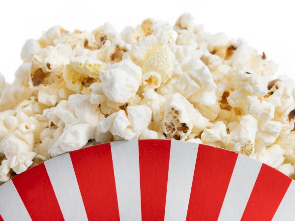 A container filled with fluffy popcorn, featuring a red and white striped design.