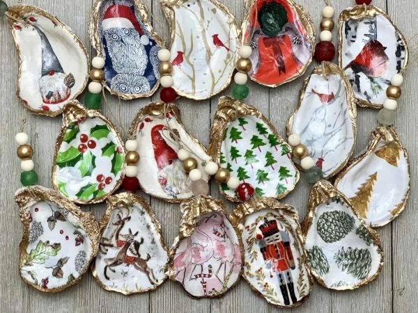 The image shows decorative oyster shells with Christmas-themed designs and beads, arranged on a wooden surface.