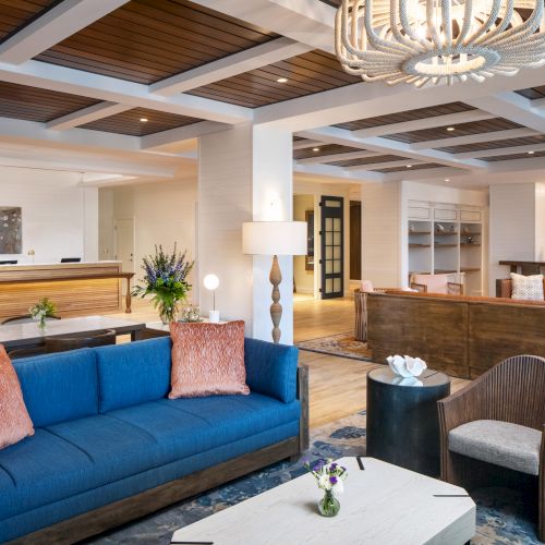 A stylish lobby with blue, brown sofas, modern furnishings, decorative plants, and unique lighting fixtures.
