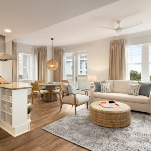 A cozy modern living space with a kitchen, dining area, and lounge. Neutral tones, sunlight, and contemporary decor characterize the room.