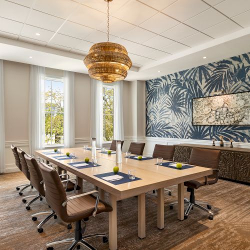 A conference room with a table, chairs, a tropical wall mural, and a decorative chandelier.